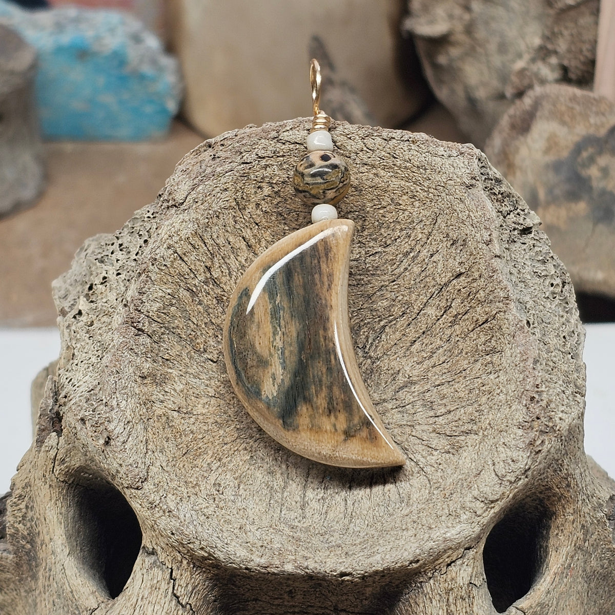 Front view of a mammoth fossil ivory crescent moon pendant with leopard-skin jasper, crafted by Kristin R Park at Ice Age Treasures.