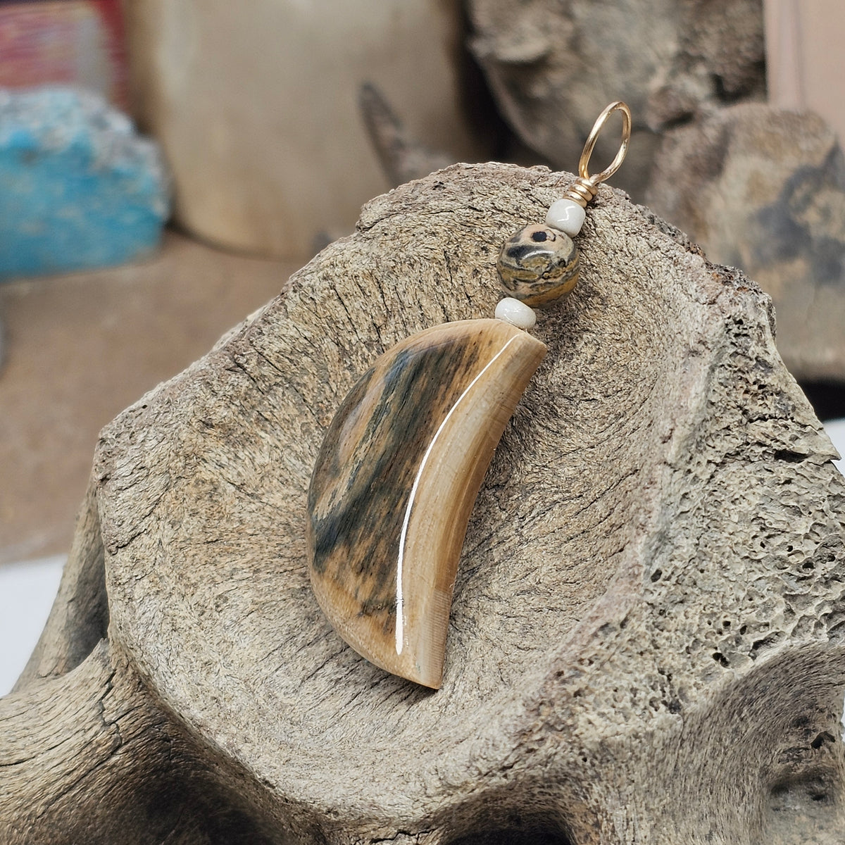 Angled view showing the polished edge and thickness of a mammoth fossil ivory moon pendant, crafted by Kristin R Park at Ice Age Treasures.