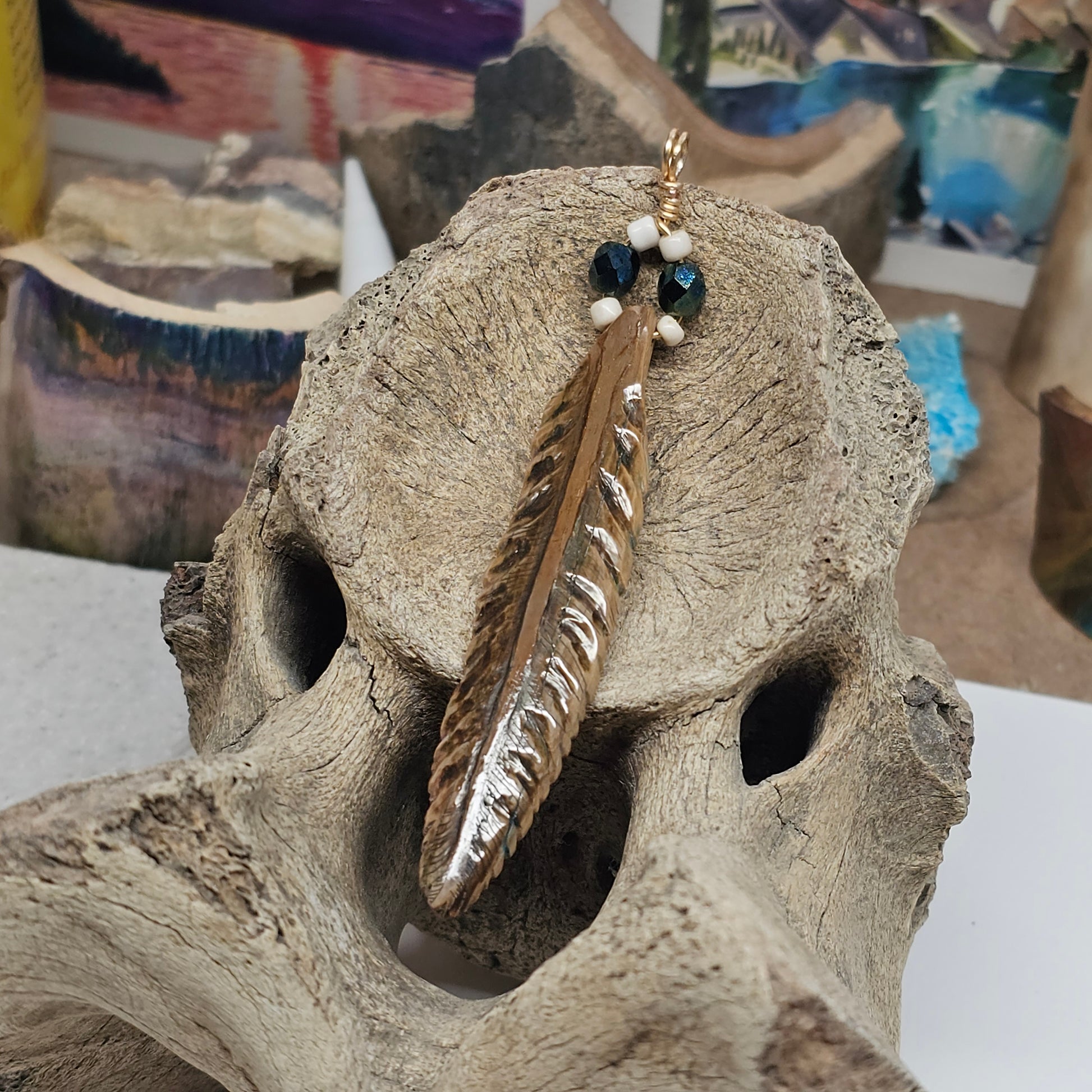 Close-up of scrimshawed feather detail on Woolly Mammoth fossil ivory pendant showing natural mineralization and Vivianite color