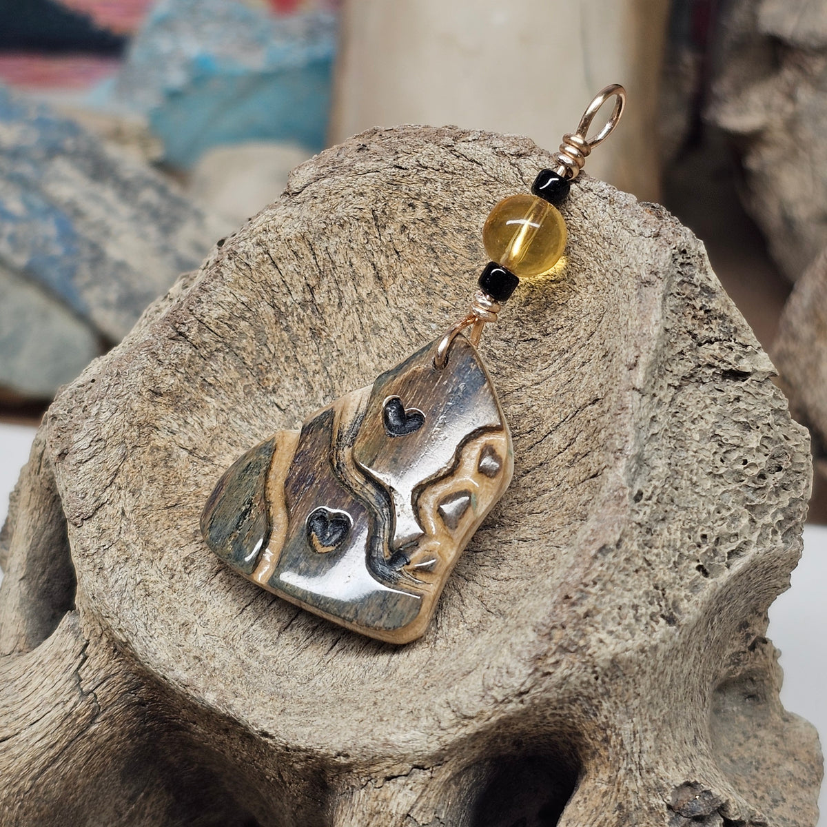 Heart Totem mammoth fossil ivory pendant with flowing carved lines, black hearts and a golden citrine bead, crafted by Kristin R Park at Ice Age Treasures.
